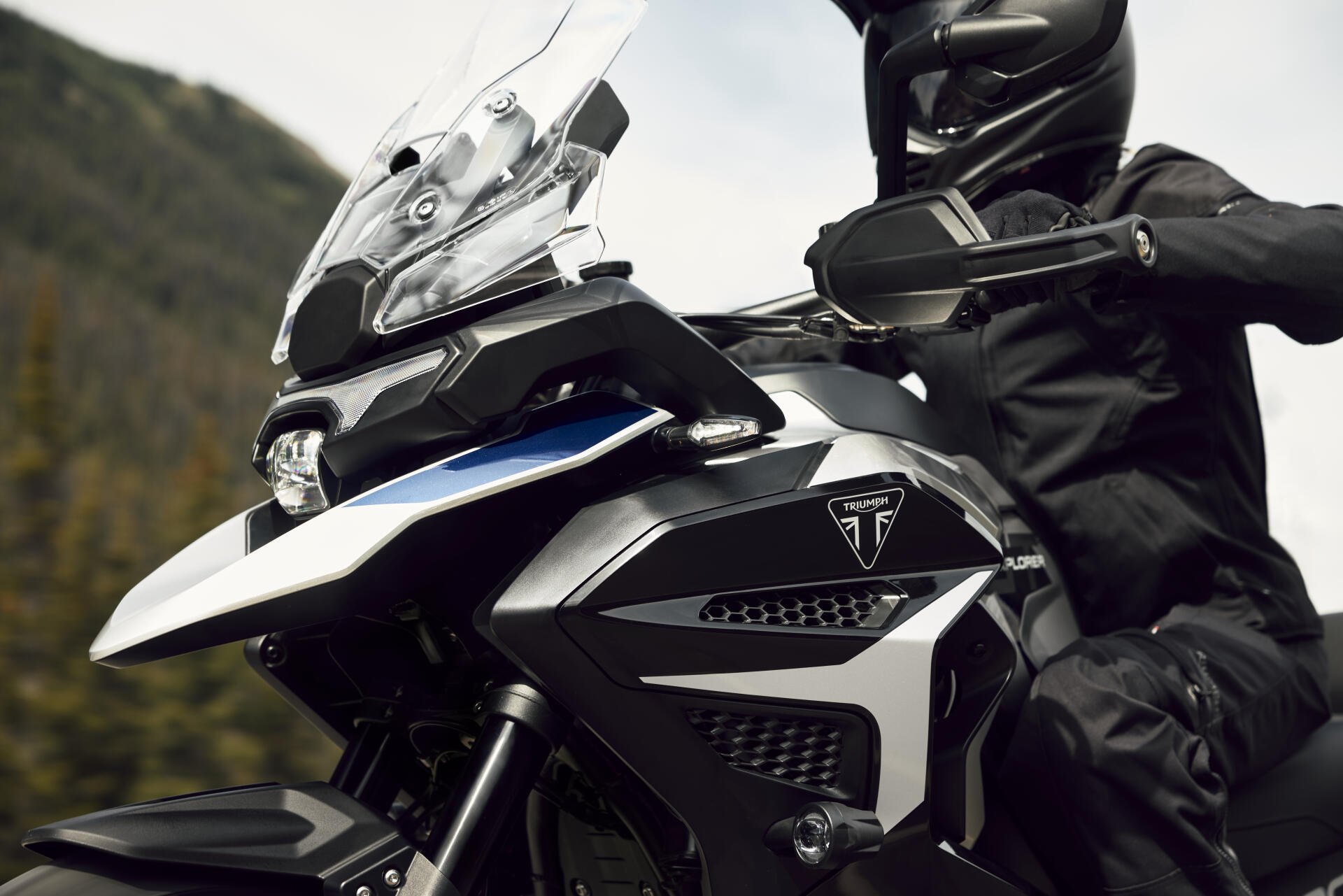 Triumph Tiger 1200 motorcycle with a helmeted motorcyclist, featured in an 8K Ultra HD desktop wallpaper.