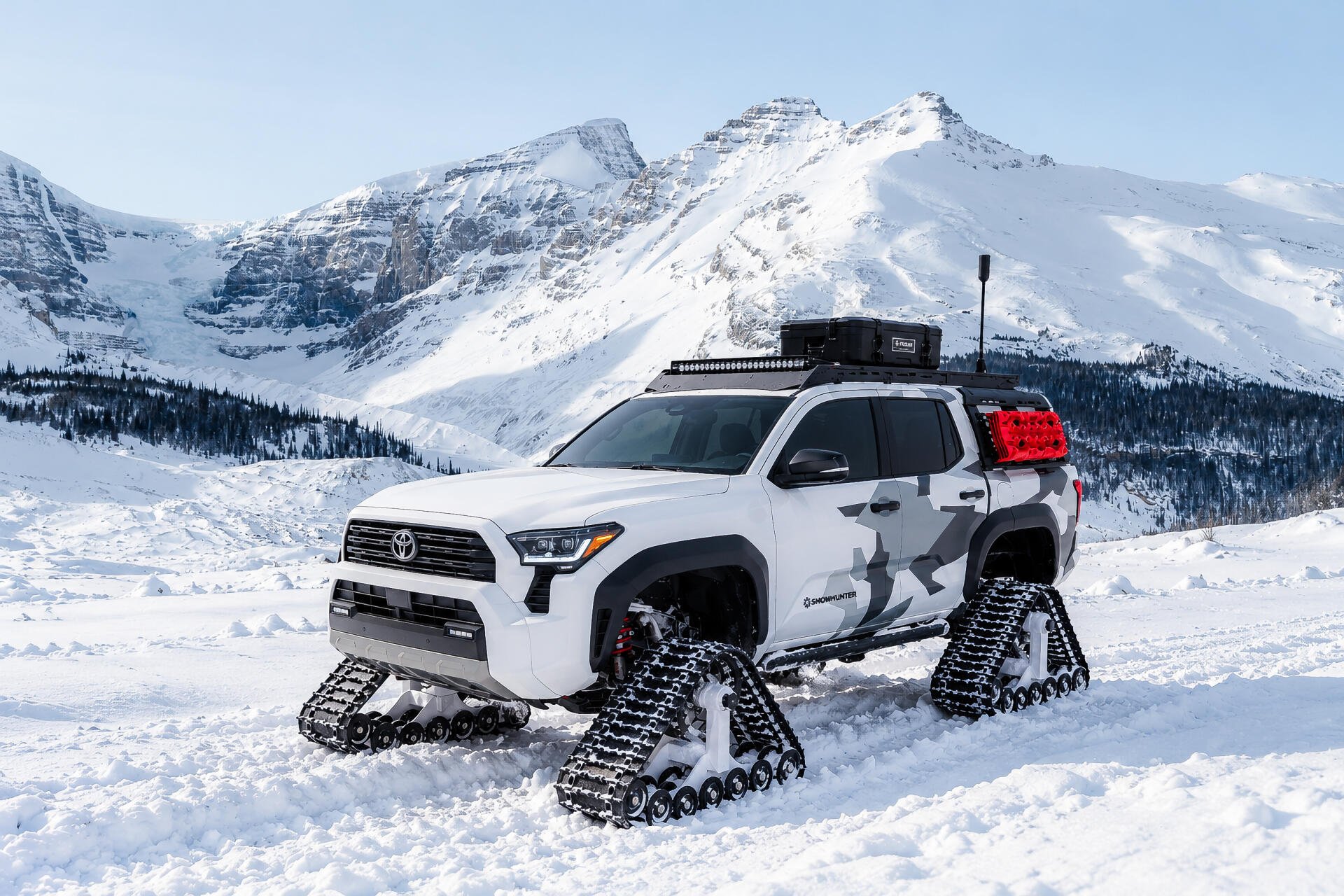 Toyota Tacoma Snowhunter truck on snow tracks in a mountain landscape, 2K Quad HD desktop wallpaper and background.