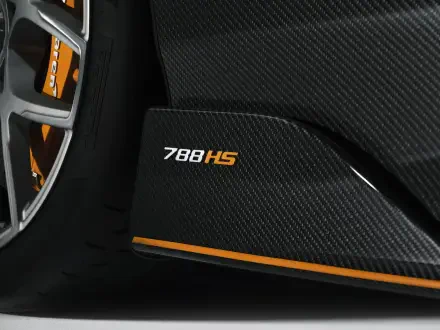 Close-up of McLaren 788HS carbon-fiber side sill and wheel with orange accent stripe — 8K Ultra HD PC desktop wallpaper