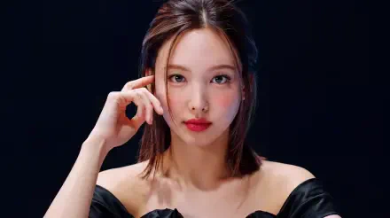 5K Ultra HD desktop wallpaper: close-up portrait of a young woman with K-pop-inspired styling—shoulder-length hair, red lips, off-shoulder black top, hand near face on dark background.