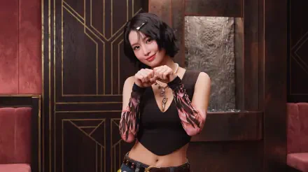 5K desktop wallpaper of a K-pop–styled woman with short black hair, wearing a black crop top and patterned arm sleeves, posing with a heart gesture against an ornate dark red and gold interior.