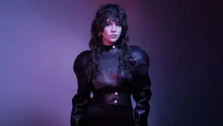 Moody portrait of a young woman in sculpted black outfit with music-inspired styling and purple lighting — 5K Ultra HD PC desktop wallpaper.