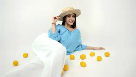 Smiling model girl in a straw hat from a photoshoot, reclining among scattered lemons — 4K Ultra HD PC desktop wallpaper/background.