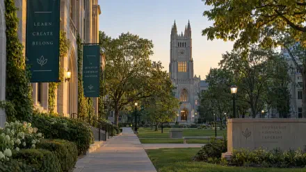 4K Ultra HD PC desktop wallpaper and background: university college campus at dusk, tree-lined walkway leading to a cathedral-style building with banners and manicured lawns.