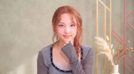 Smiling young woman with braided hair and a gray top in a soft pastel studio, K-pop idol–styled 5K desktop wallpaper.