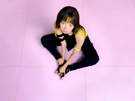 IVE Rei model in a black and yellow outfit against a pink backdrop, featured in Looks Can Kill 4K Ultra HD desktop wallpaper.