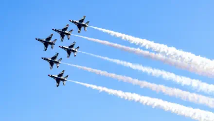 United States Air Force Thunderbirds F-16 jet fighters soar in formation at an air show, leaving white smoke trails across a blue sky; 5K Ultra HD desktop wallpaper.