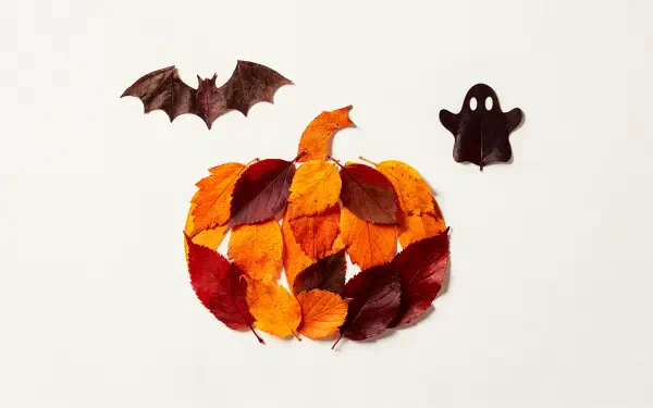Minimal Halloween 4K Ultra HD PC desktop wallpaper: pumpkin made of orange, red and brown leaves, flanked by a bat and a small ghost cutout on a white background.
