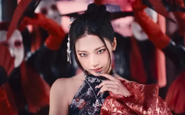 5K Ultra HD K-pop–styled PC wallpaper: close-up of a woman in ornate red-and-black outfit, dramatic makeup and hair accessories, hand near face, shadowy dancers behind her.