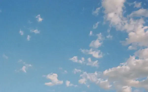 Soft scattered white clouds drift across a vivid blue sky — 4K Ultra HD PC desktop wallpaper background.
