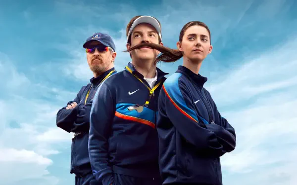4K Ultra HD PC desktop wallpaper: three coaches in navy tracksuits in a Ted Lasso–inspired pose, mustached coach center, arms-crossed teammates against a bright cloudy sky.