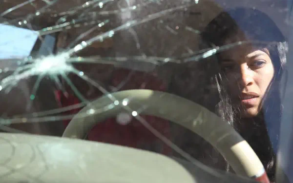 Close-up of a woman behind a cracked windshield, brooding cinematic shot from Miss Bala — 4K Ultra HD PC desktop wallpaper and background.