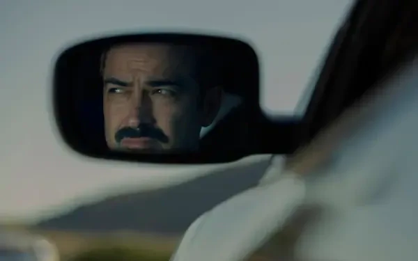 4K Ultra HD PC desktop wallpaper: mustachioed man’s intense face reflected in a car rearview mirror, confronting an unseen presence—tense, cinematic close-up.