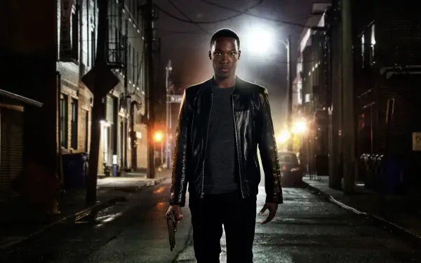24: Legacy — 4K Ultra HD PC desktop wallpaper: a lone man in a leather jacket walks down a dim, rain-slick city alley at night, backlit by car headlights, holding a handgun.