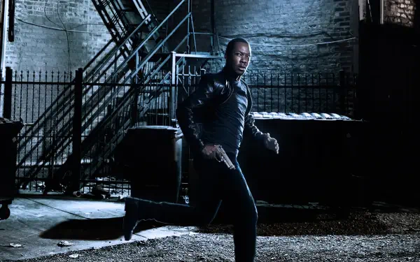 24: Legacy — man in a leather jacket aims a pistol while crouching in a dim, gritty urban alley; 4K Ultra HD PC desktop wallpaper/background.