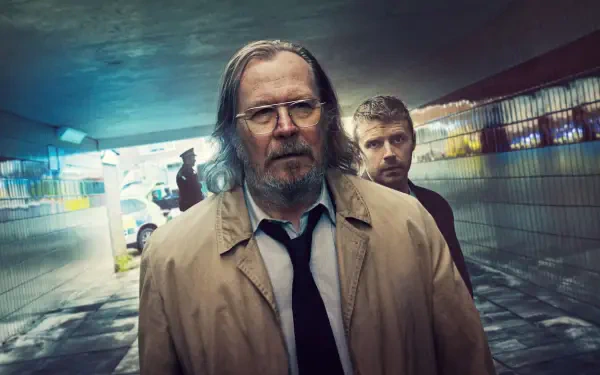 4K Ultra HD PC desktop wallpaper of two weary figures in trench coats in a rain‑slick tiled underpass, moody blue‑green lighting and neon reflections — Slow Horses.