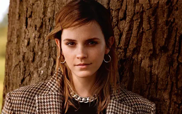 Close-up portrait of a young woman in a houndstooth coat with hoop earrings leaning against a tree — 2K Quad HD PC desktop wallpaper/background.