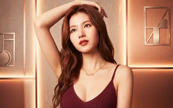 5K desktop wallpaper: portrait of a young woman with long brown hair in a burgundy camisole, posing against a warm, geometric lit wall.