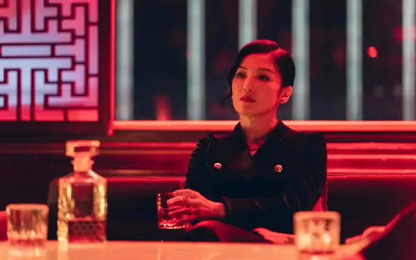 Cinematic 8K Ultra HD portrait of a woman from The Fixers seated in a red-lit bar, holding a glass — striking PC desktop wallpaper.
