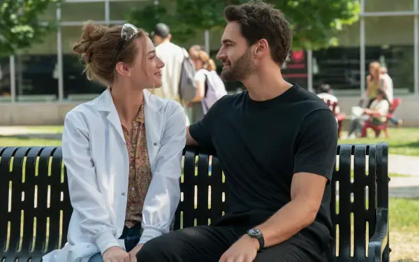 The Love Hypothesis — a couple sit close on a park bench, smiling and gazing at each other; 4K Ultra HD PC desktop wallpaper/background.