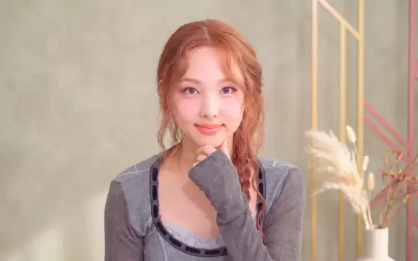 Smiling young woman with braided hair and a gray top in a soft pastel studio, K-pop idol–styled 5K desktop wallpaper.