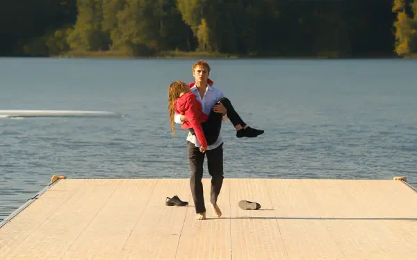 4K Ultra HD PC desktop wallpaper: Crew Girl Netflix couple on a sunlit dock, a man carrying a woman across a calm lake.
