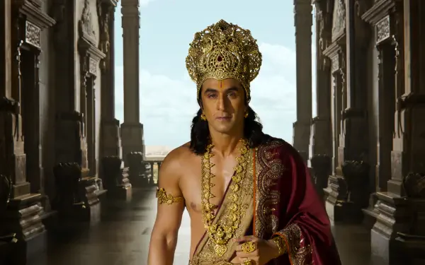 Actor in Ramayana (2026) as a royal king wearing an ornate gold crown and red cloak in a palatial corridor — 4K Ultra HD PC desktop wallpaper background.
