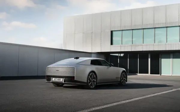 Jaguar Type 01 electric sedan parked outside a modern building, featured in a 5K Ultra HD PC desktop wallpaper.