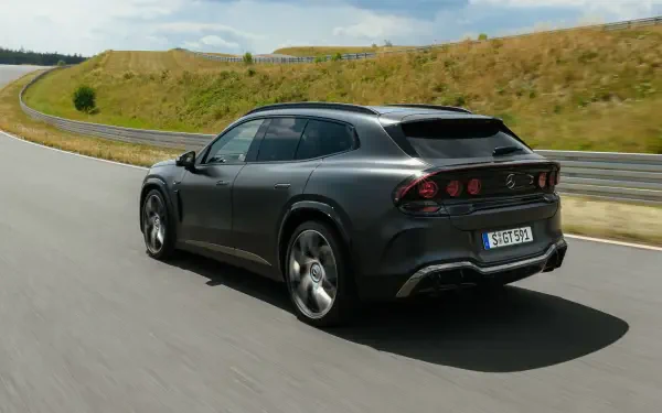 Dark gray Mercedes-AMG GT SUV sports car driving on a winding road, featured in a 2K Quad HD desktop wallpaper background.