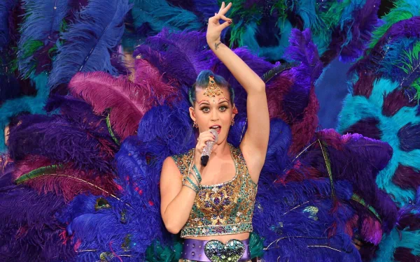 Vibrant HD wallpaper featuring Katy Perry performing, adorned in a dazzling outfit with colorful feathers behind her, capturing the energy of her music and stage presence.