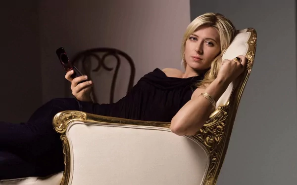Maria Sharapova relaxes elegantly on a luxurious chair, holding a remote in a chic black outfit. This HD wallpaper captures her poise in a stylish setting, celebrating sports and sophistication.
