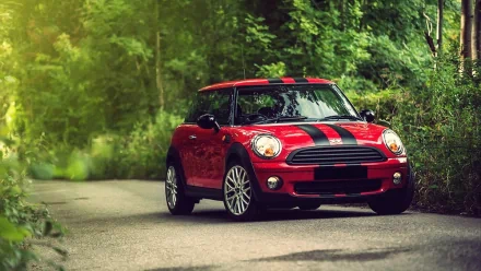A vibrant red Mini Cooper parked on a winding road surrounded by lush greenery, creating a striking HD desktop wallpaper and background.