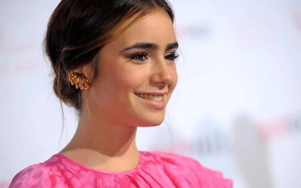 Lily Collins smiles brightly in a vibrant pink dress, showcasing her elegant style in this HD PC desktop wallpaper. A captivating image of the celebrated actress.