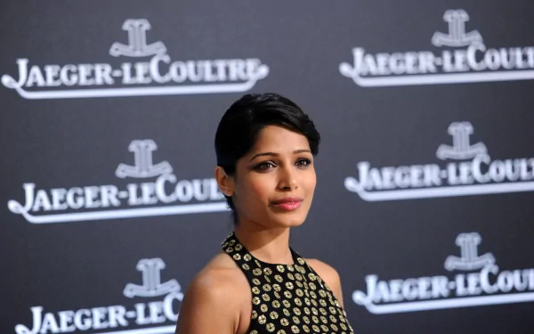 Freida Pinto, an actress with black hair, poses elegantly against a stylish backdrop featuring Jaeger-LeCoultre branding, captured in stunning 4K Ultra HD.