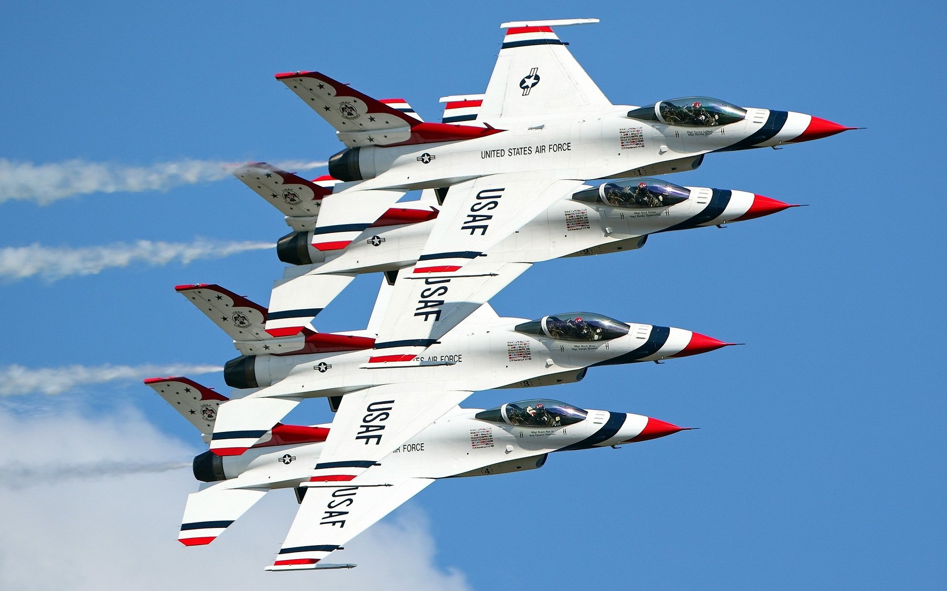 Four US Air Force jets in tight formation perform a military air show maneuver against a clear blue sky, captured in high definition as a desktop wallpaper background.