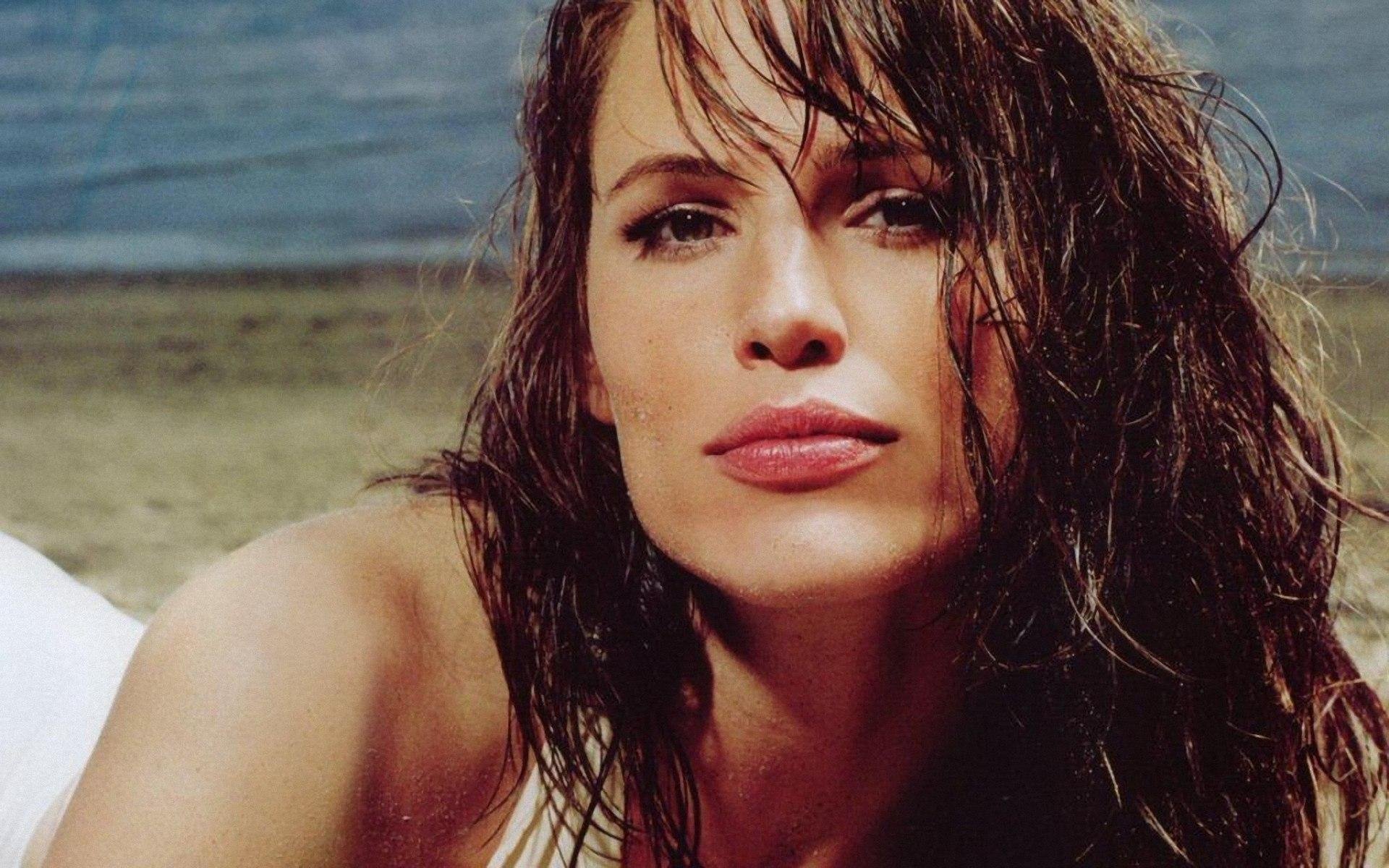 HD PC desktop wallpaper: close-up celebrity portrait of a wet‑haired woman on a beach, intense direct gaze.