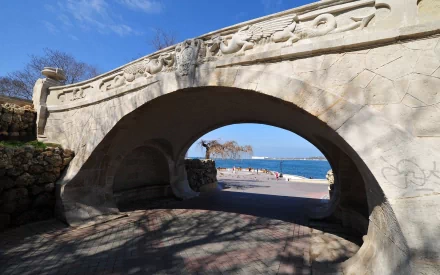 HD desktop wallpaper showcasing a historic stone bridge in Sevastopol, with a scenic view of the coastline and clear blue sky in the background.