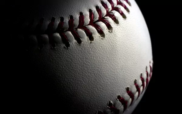 Close-up HD desktop wallpaper of a white baseball with red stitching, highlighting its texture and detail against a dark background in a sports-themed image.