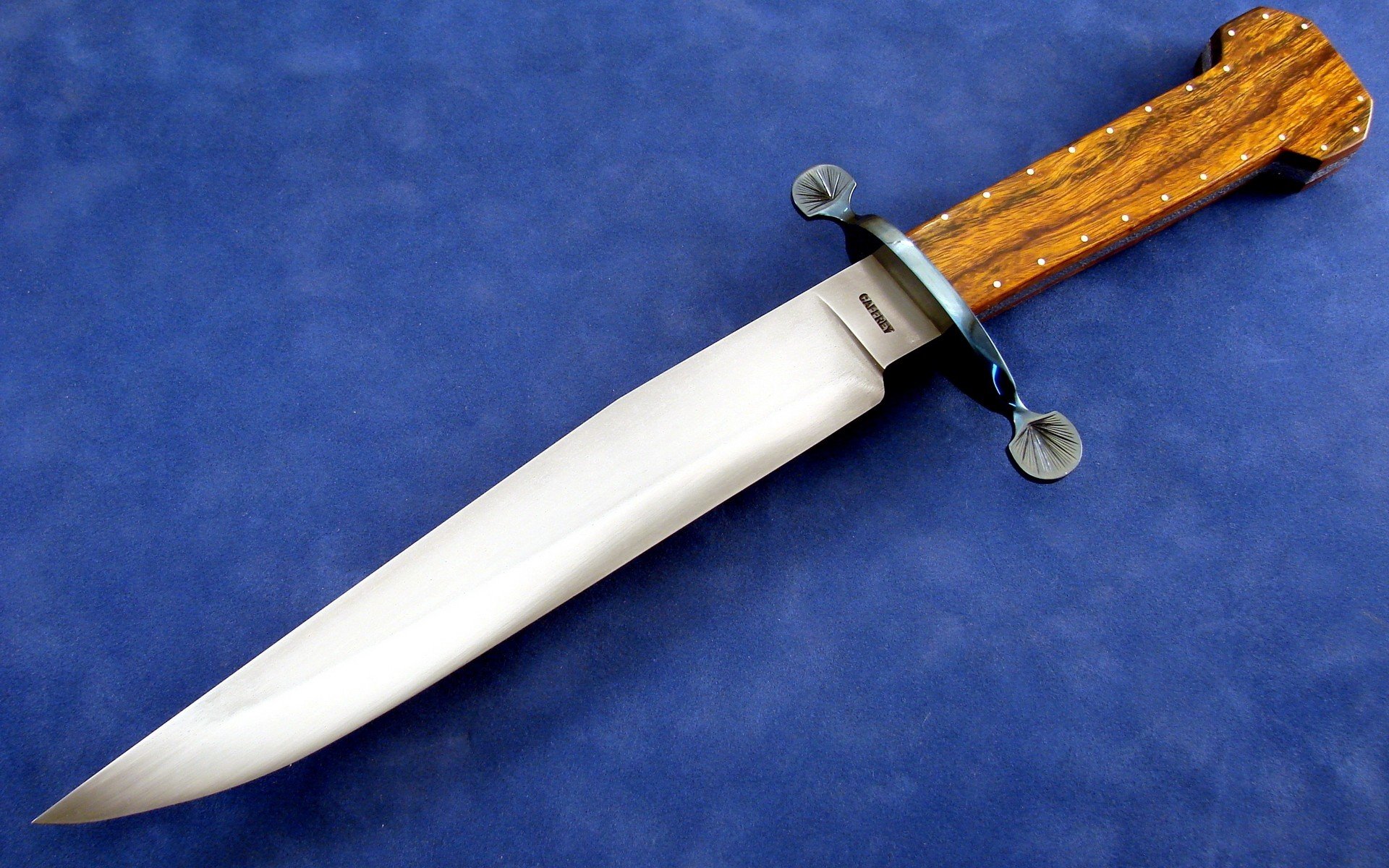 A high-definition desktop wallpaper featuring a man-made knife with a polished blade and intricately designed wooden handle, set against a blue background.