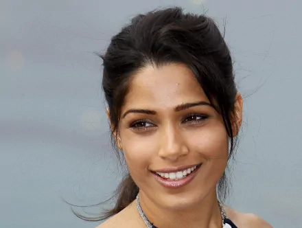 HD desktop wallpaper featuring Freida Pinto, showcasing her smiling warmly against a softly blurred background.