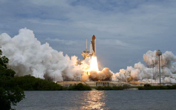 HD desktop wallpaper showing a space shuttle vehicle launching with flames and smoke against a partly cloudy sky over water.