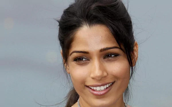 HD desktop wallpaper featuring Freida Pinto, showcasing her smiling warmly against a softly blurred background.