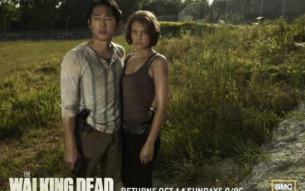 Maggie Greene and Glenn Rhee from the horror TV show The Walking Dead stand together in a grassy field, embodying the tension and resilience of their characters.