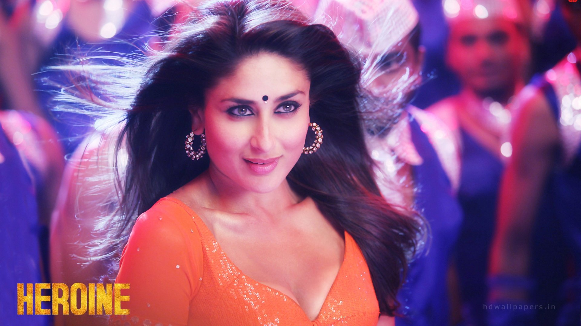 HD desktop wallpaper featuring celebrity Kareena Kapoor in an orange outfit, with a focused and captivating expression, set against a vibrant background.