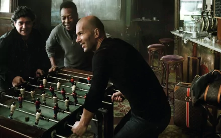 Three legendary soccer players—Zinedine Zidane, Diego Maradona, and Pelé—enjoy a game of foosball, exuding camaraderie and passion for sports in this vibrant HD wallpaper.