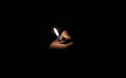 Photography: close-up of a hand holding a lit lighter, fire glowing against deep black — HD PC desktop wallpaper and background.
