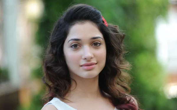 HD PC desktop wallpaper of a young woman with wavy dark hair and a gentle smile set against a soft, blurred green outdoor background.
