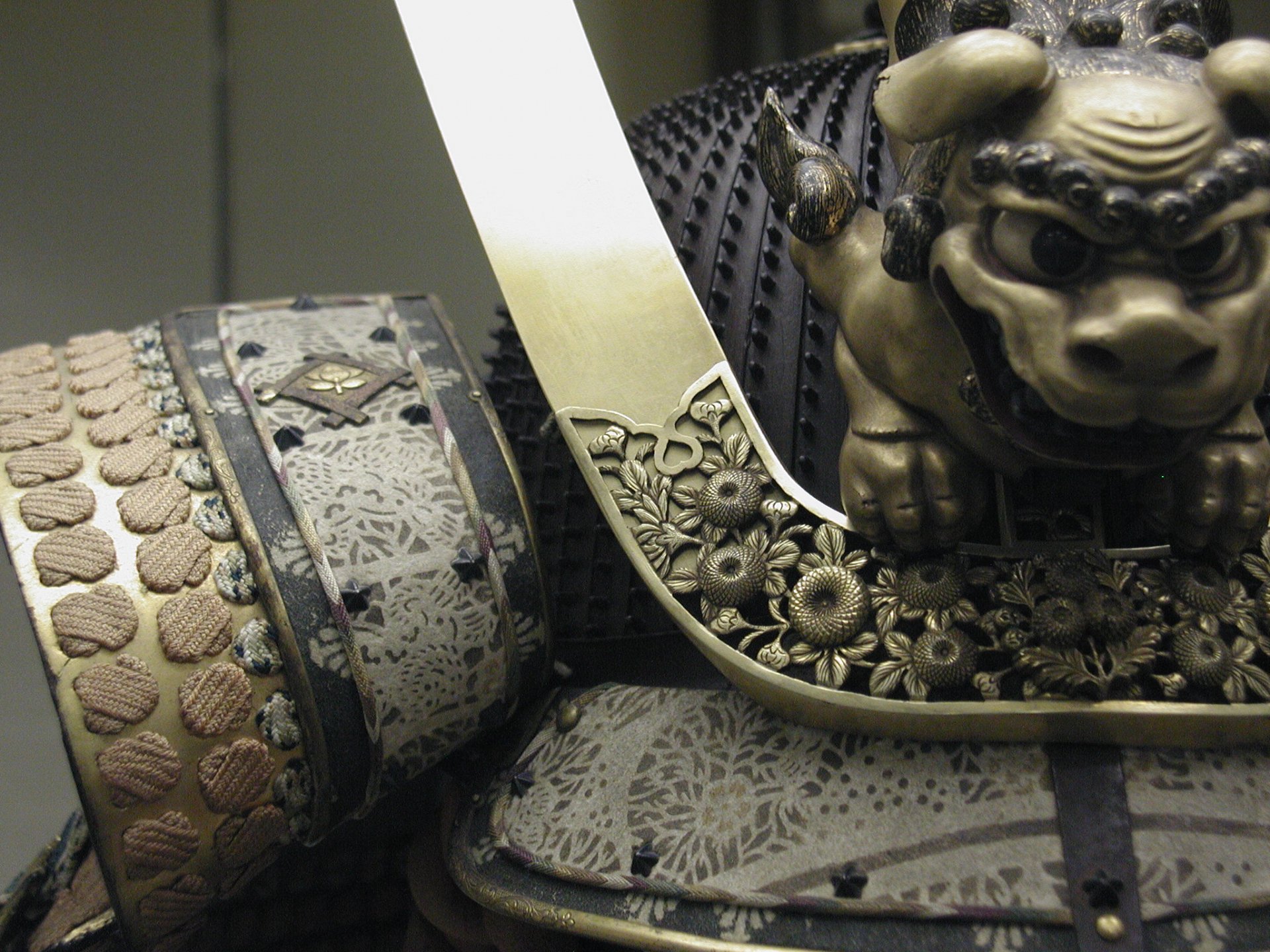 HD PC desktop wallpaper and background: close-up of man-made ornate samurai armor—engraved metal fittings, floral motifs, lion ornament and braided leather padding.