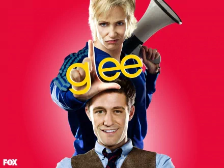 HD PC desktop wallpaper of two Glee TV show characters: a stern coach with a megaphone stands behind a smiling teacher, the yellow glee logo centered on a bright red background.