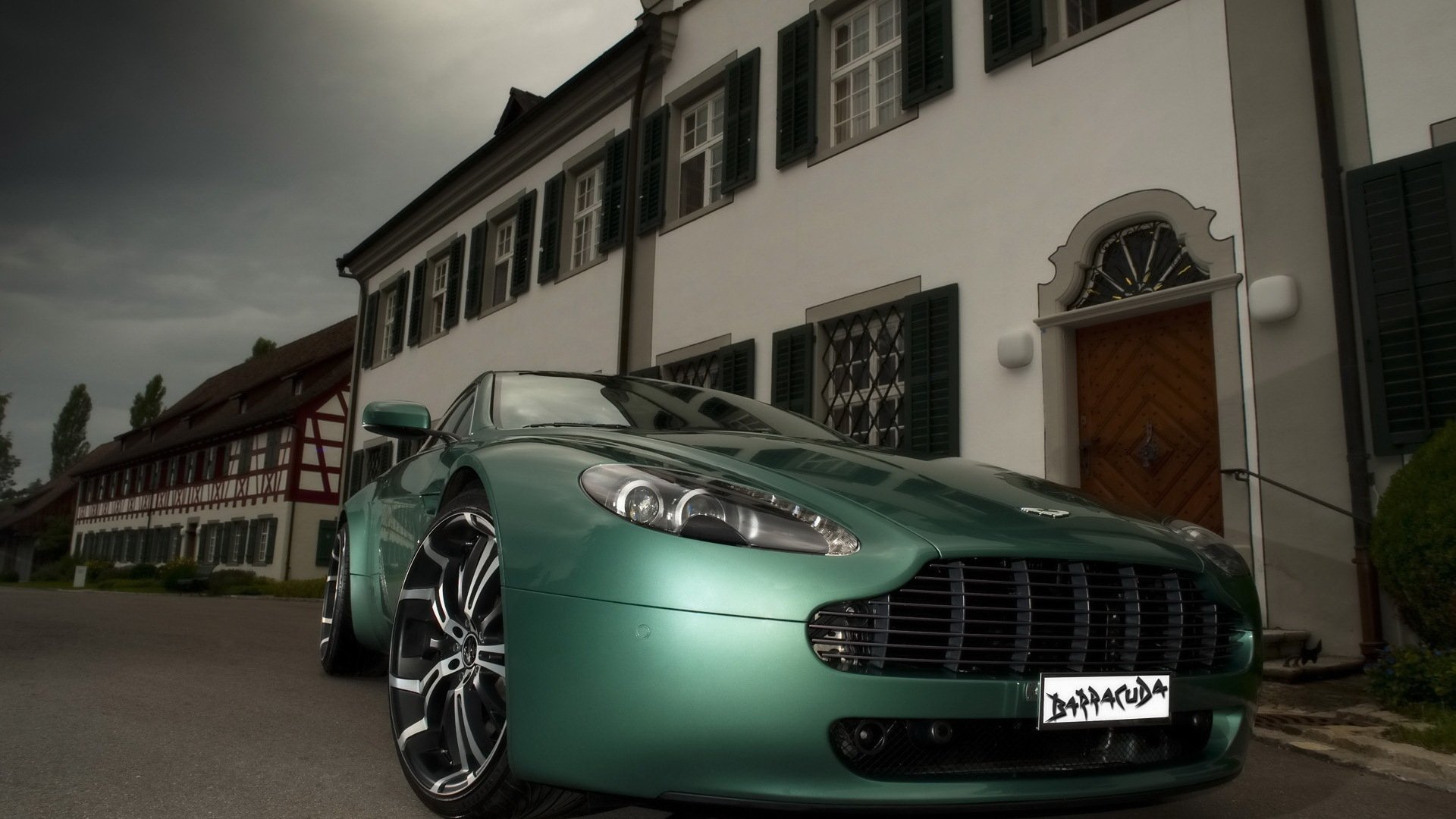 Green Aston Martin Vantage vehicle parked before a European manor under a moody sky — HD PC desktop wallpaper and background, sleek sports-car profile.